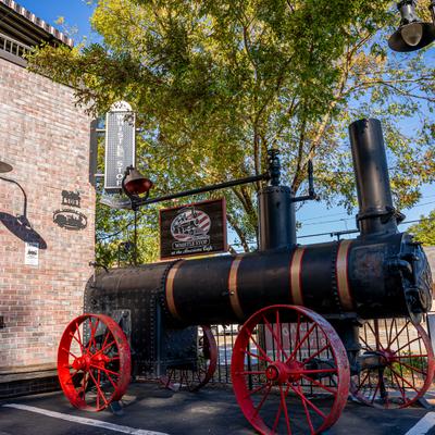 A vintage black steam engine with red wheels displayed outside the restaurant.
