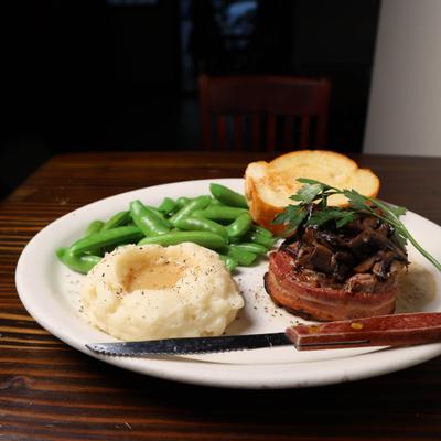Bacon wrapped filet mignon with mash potatoes , snap peas and toasted french bread.
