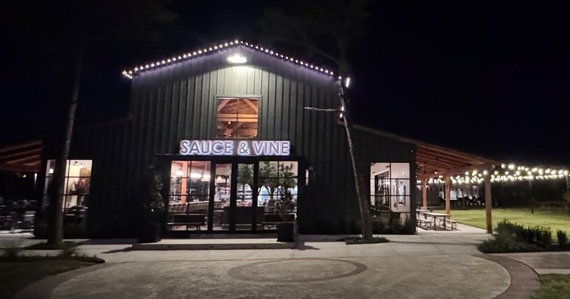 Nighttime view of Sauce & Vine building with string lights