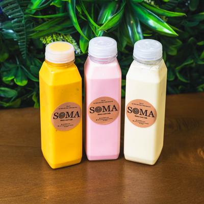 Three colorful Soma bottled drinks on a wooden table.