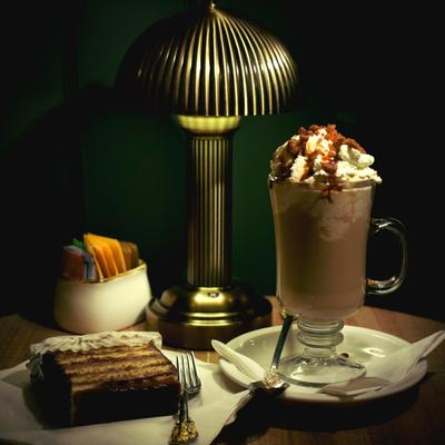 Hot chocolate with whipped cream beside layered cake slice.