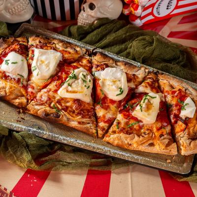Burrata and Honey Flat Bread sliced and served on a wooden board.