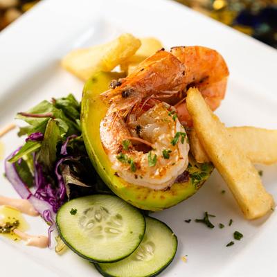 Grilled shrimp in an avocado half with salad and fries.