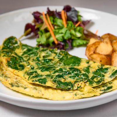 Spinach omelet served with roasted potatoes and a salad.