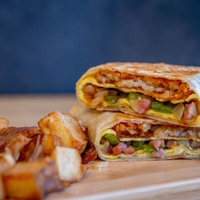 West Coast Burrito served on a wooden board with home fries.