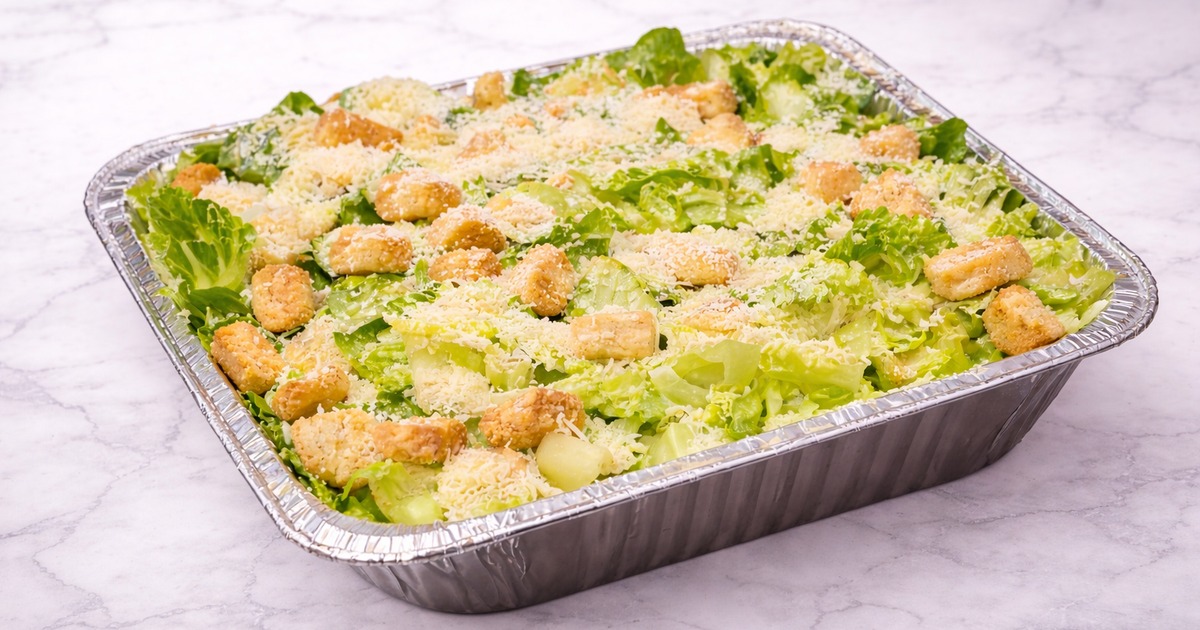 Large tray of caesar salad topped with croutons and grated cheese