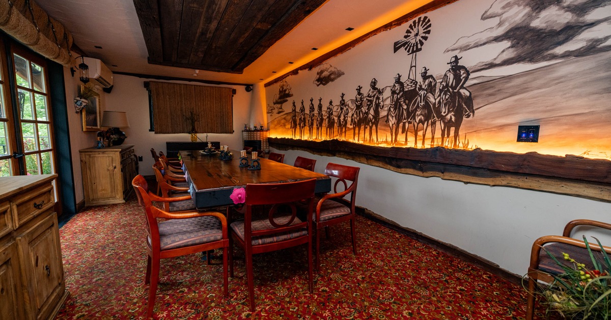 Rustic dining room with a large wooden table, chairs, floral carpet