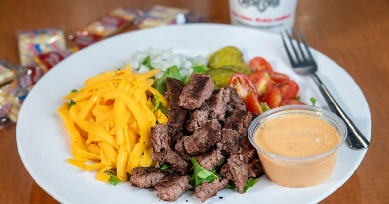Cheeseburger salad served with a dip, alongside a drink