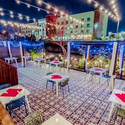 A nighttime patio scene with, string lights,  tables and chairs.