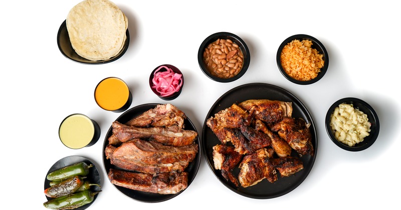 Meat served on two plates, accompanied with assorted side dishes