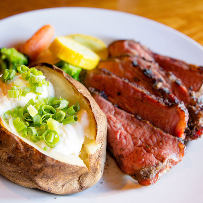 Steak slices with bread with cream and spring onions and veggies on the side