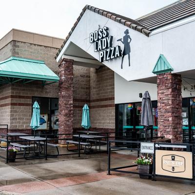 Exterior with signage, outdoor seating, and closed parasols.