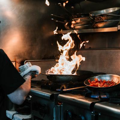 Chef cooking with an open flame in a restaurant kitchen.
