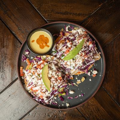 Two Wild Caught Shrimp tacos on a plate with salsa, atop a wooden table.