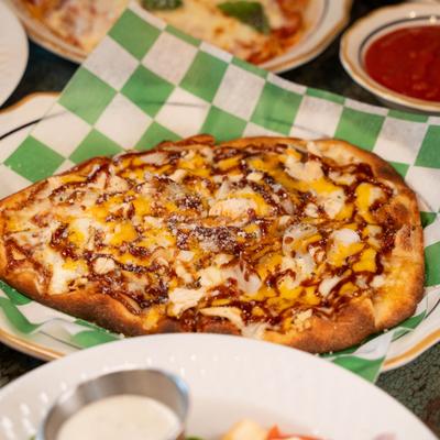 Pizza with roasted chicken, BBQ sauce, mozzarella, cheddar, and onions.