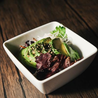 A fresh avocado salad in a white square bowl.