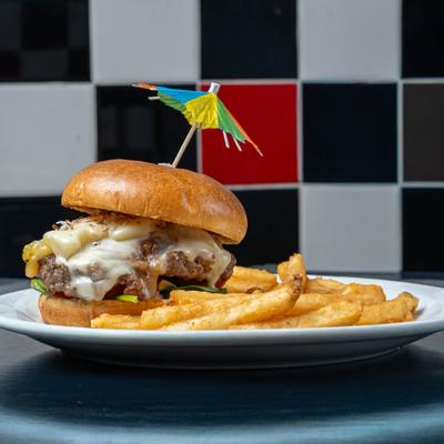 Inferno Burger served with a cocktail umbrella garnish and a side of fries.