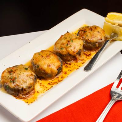 Stuffed mushroom caps covered in melted cheese, served on a rectangular plate