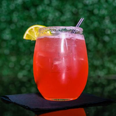 The District, red colored cocktail with lemon wedge garnish.