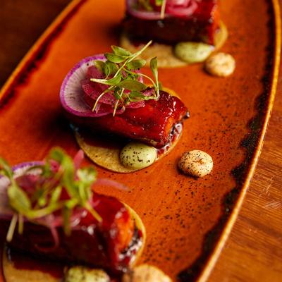 Glazed pork belly bites, with pickled onions, poblano cream, radish, and micro cilantro.