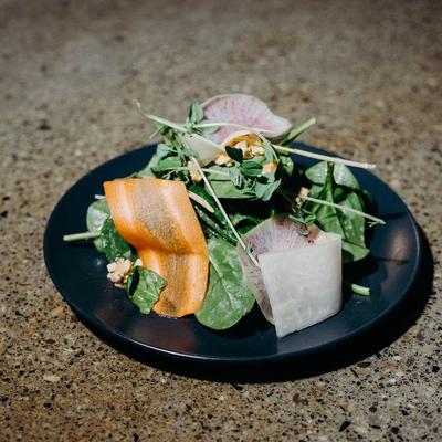 A fresh salad featuring spinach, radish, nuts, and herbs.