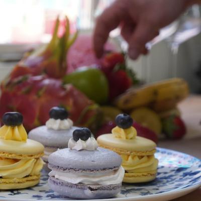 Assorted macaroons with fresh fruit in the background.