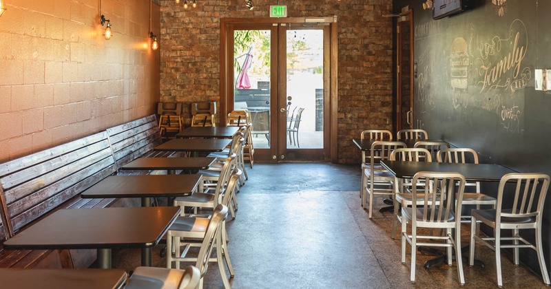 Interior, seating by a wall with lined up tables and chairs, tables for four