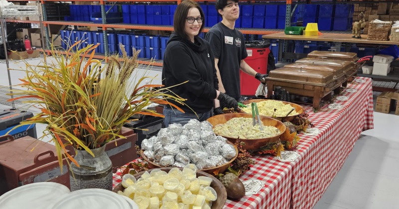 Buffet setup with two servers and assorted dishes on a checkered table