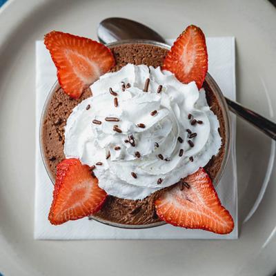 Chocolate mousse topped with whipped cream and strawberry.
