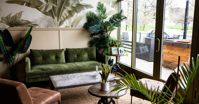Interior, tufted upholstered seating with a coffee table, potted plants