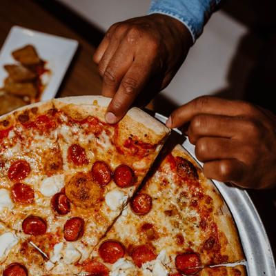 A man pulling a piece of pica from the whole pie, closeup.