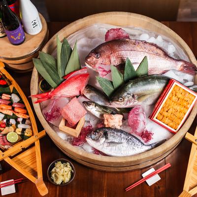 Assortment of dishes, fresh fish platter, sushi boats and sake, overhead view.