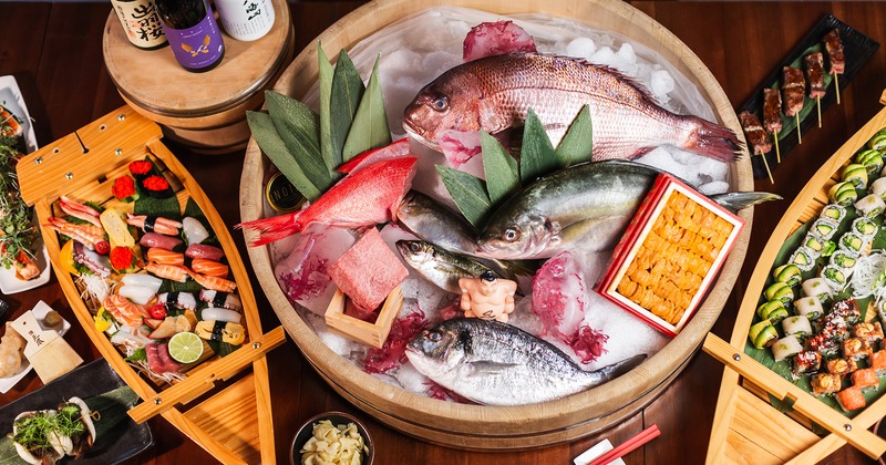 A top view of a table with displayed fresh fish catch and sushi boats