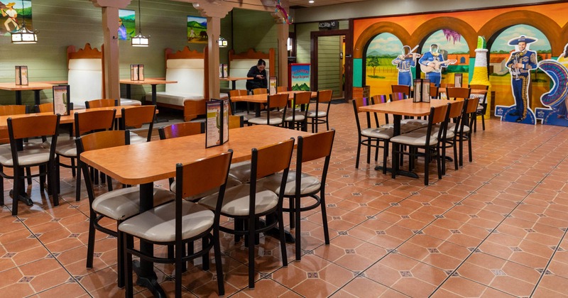 Interior, dining area, tables for six, seating booths in the back, colorful mural on the wall