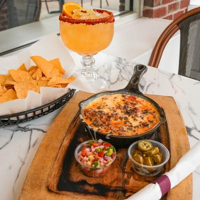 Chorizo and cheese dip, with tomato salsa, pickled jalapenos, tortilla chips, and Margarita.