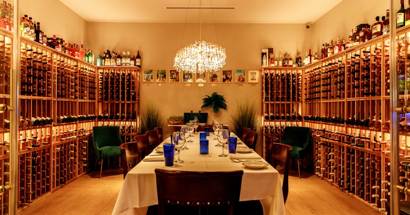 An elegant setup in a private wine room with a long table set for an upscale gathering