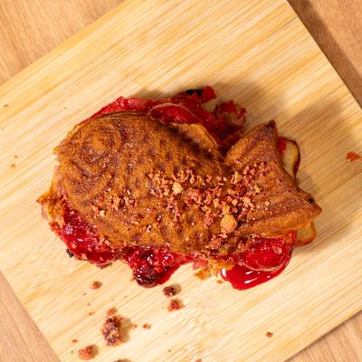 Taiyaki dessert with strawberry flavor, served on a wooden board.
