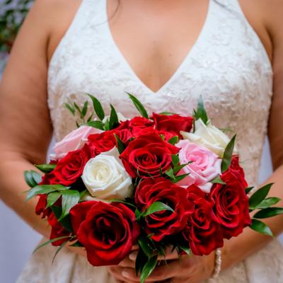 Bridal bouquet with red, white and pink roses held by a bride, closeup