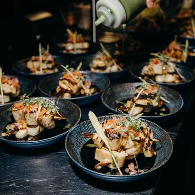 Plates of grilled seafood dishes garnished with herbs and vegetables.