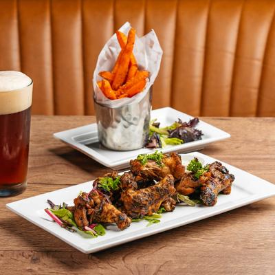 Jerk chicken, sweet potato fries, and a glass of beer.
