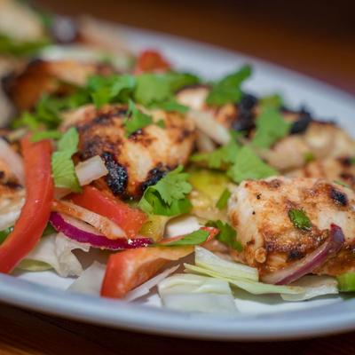 Grilled chicken salad with onions, red peppers, lettuce, and cilantro.