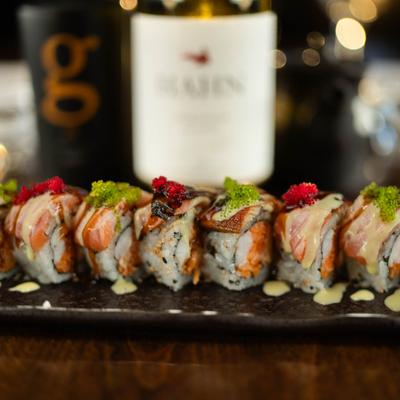 Tiger Roll topped with fish roe and drizzled with sauces.