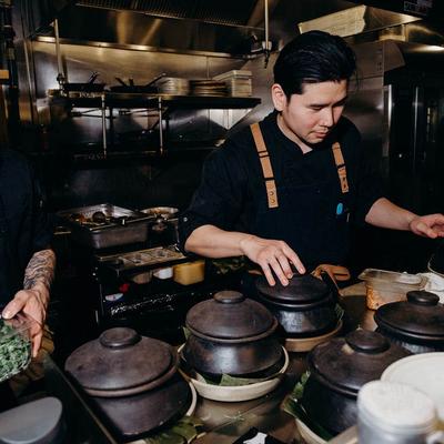 Chef preparing food surrounded by clay pots.