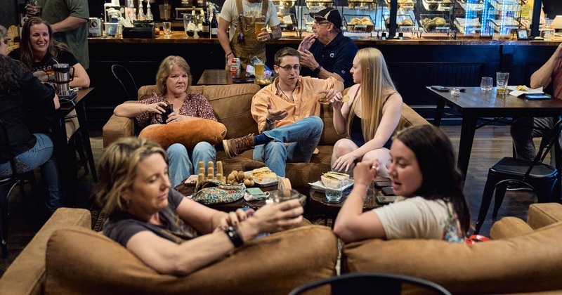 Groups of people socializing and enjoying food and drinks in seating area