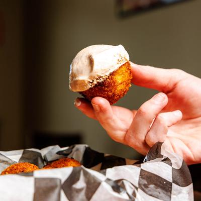 Hand holding a tater tot dipped in sauce.