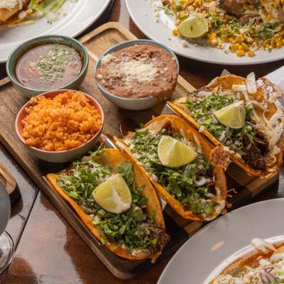 Birria tacos, with onion, cliantro, rice, beans, and consomme.