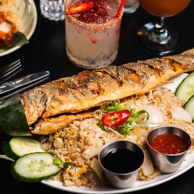 Whole fried branzino with fried rice, accompanied by dipping sauces and a spicy margarita.