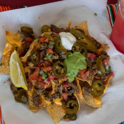 Nachos, with ground beef, melted cheese, tomato, jalapenos, guacamole, and sour cream.