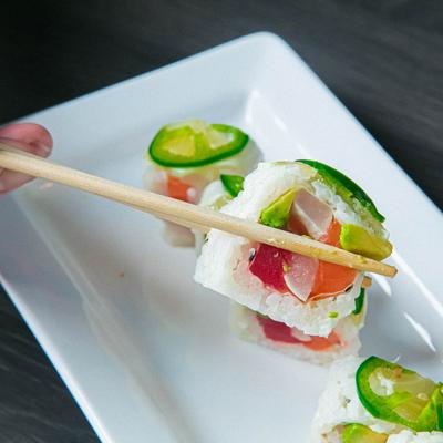 Sammy Roll piece held in chopsticks, close up.