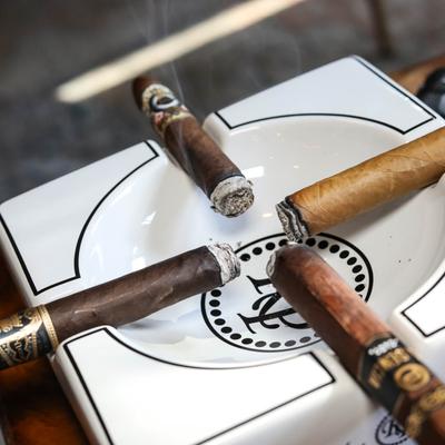 Four lit cigars in an ashtray